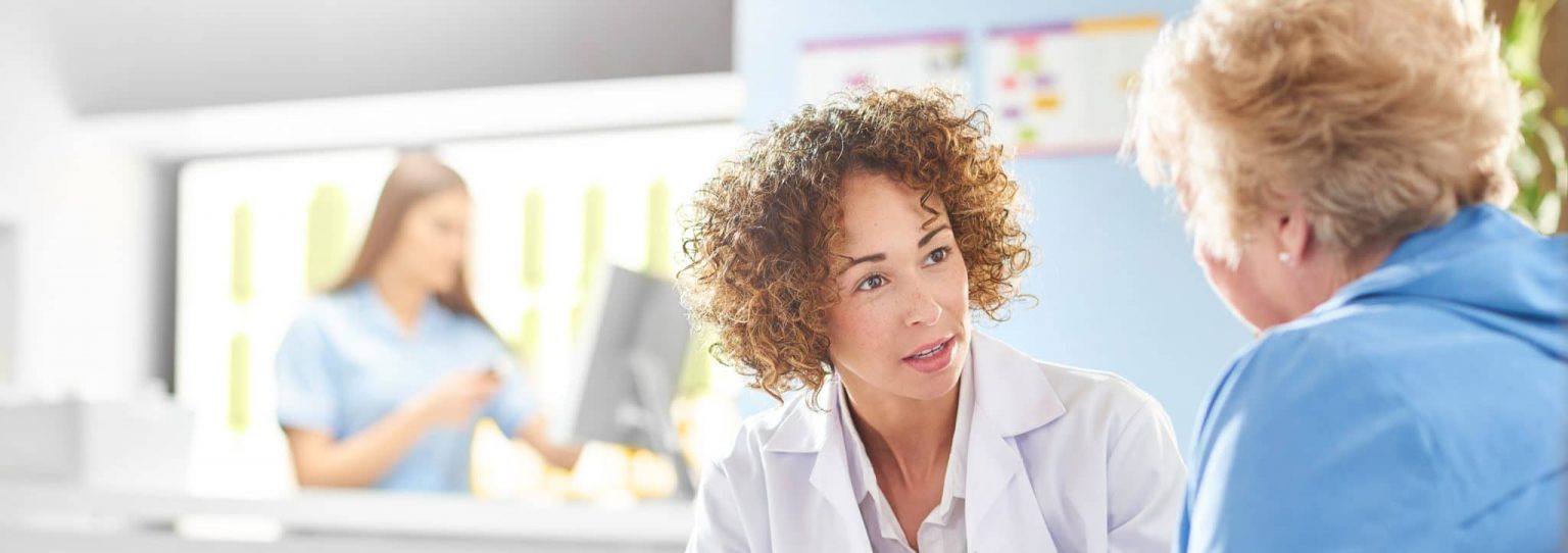 voice-disorders-evaluation Doctor discussing voice disorders with patient.